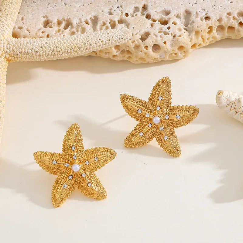18K gold-plated starfish earrings with zirconia and simulated pearls on a light background
