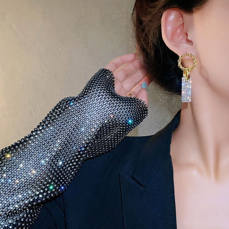Woman wearing a gold and crystal statement earring with sparkling mesh glove
