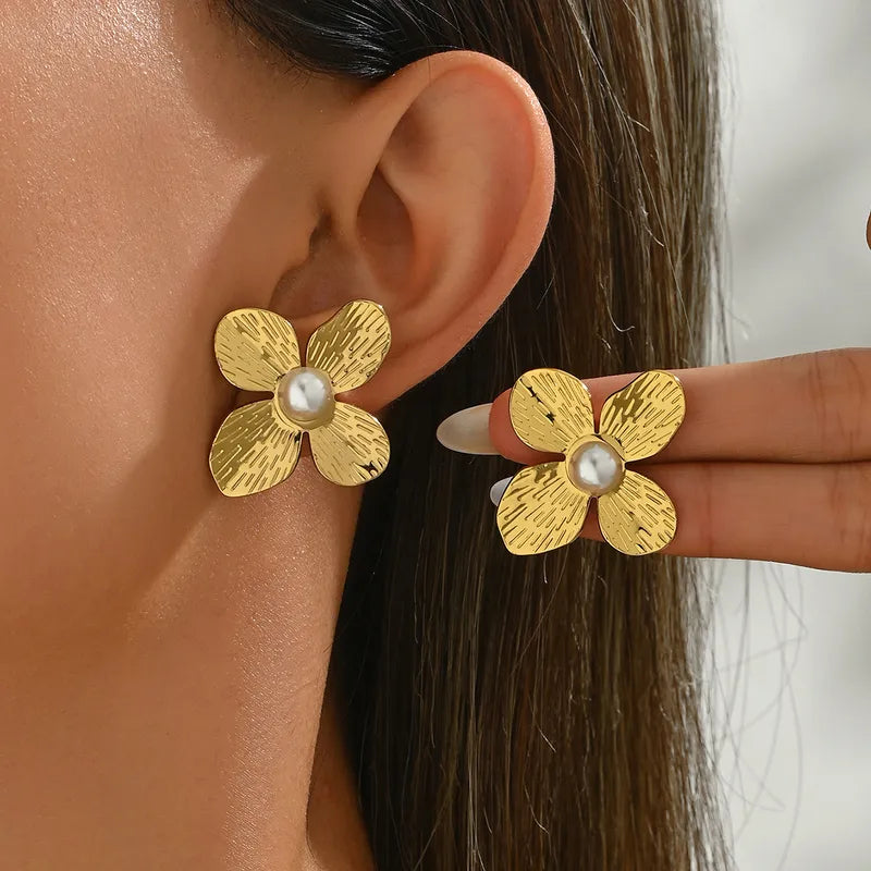 Gold plated flower stud earrings with pearl center, worn on ear, elegant and stylish design