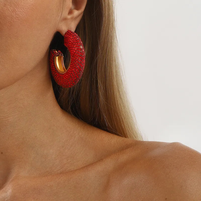 Red full diamond C-shaped hoop earring with gold detail on woman's ear, geometric design